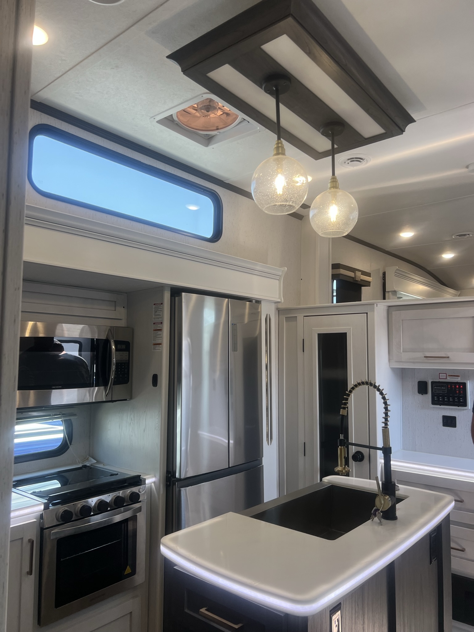 Full RV kitchen with island, refrigerator, range, and microwave